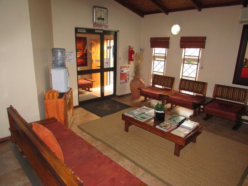 A welcoming office reception area featuring tiled floors, exposed timber ceiling beams, and natural light through lattice-style windows.