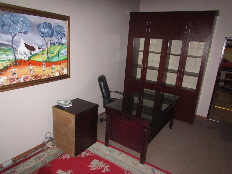 A functional office space featuring built-in dark wood cabinetry and carpeted flooring, providing a professional environment for work or study.