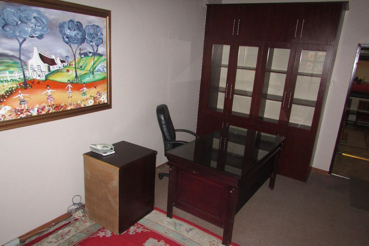 A functional office space featuring built-in dark wood cabinetry and carpeted flooring, providing a professional environment for work or study.