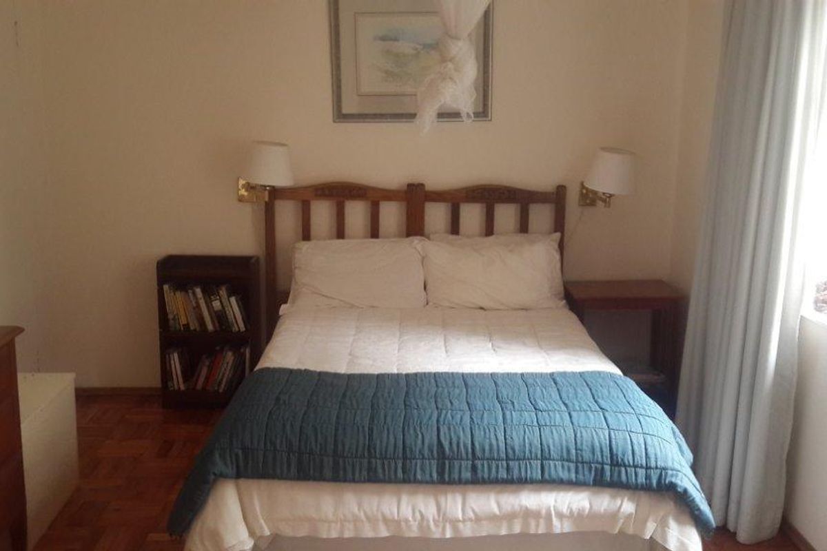 A cozy bedroom featuring classic parquet flooring and wall-mounted lighting, offering a comfortable and functional sleeping space.