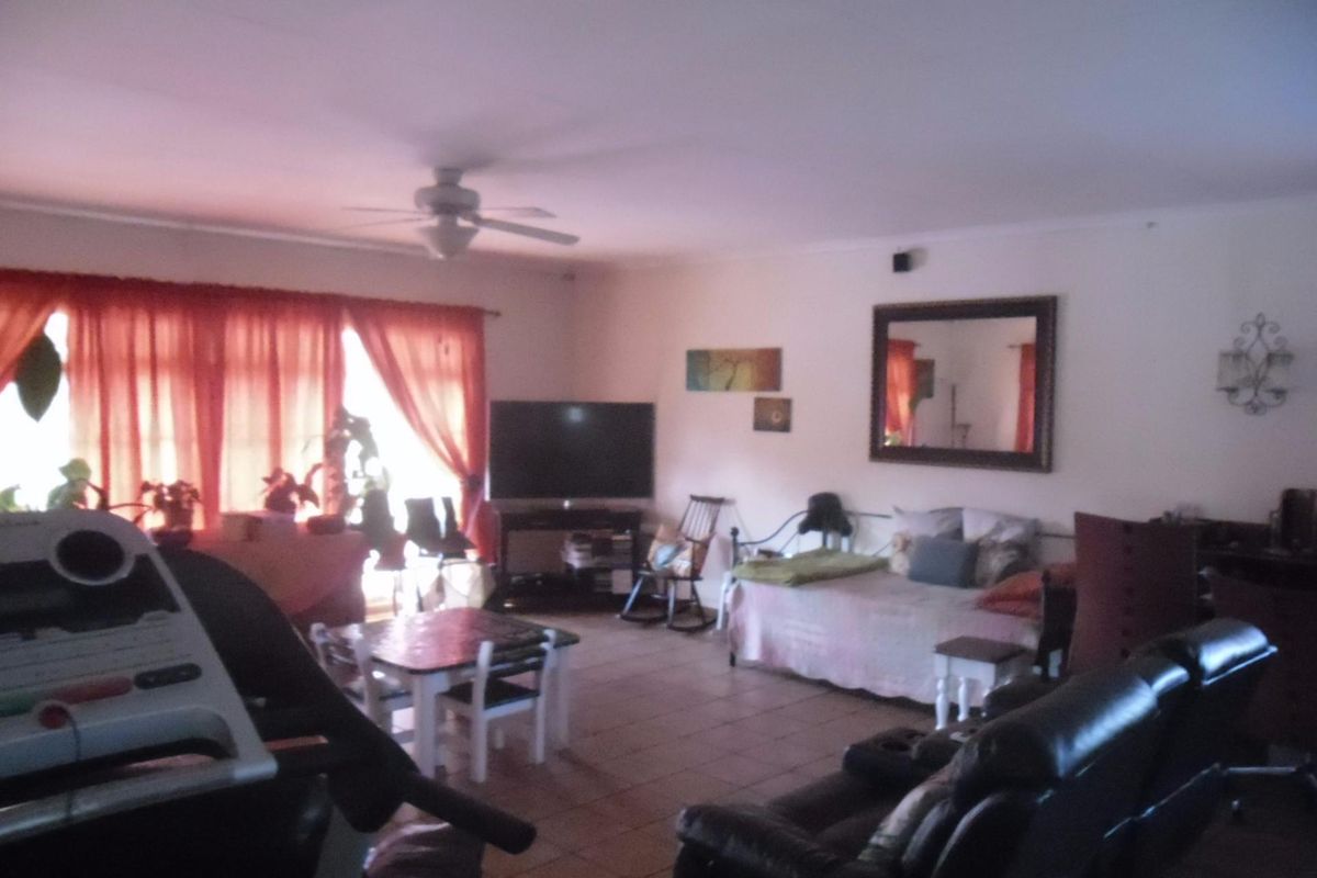 Spacious living area featuring tiled flooring and a ceiling fan, offering a versatile layout for comfortable family living.