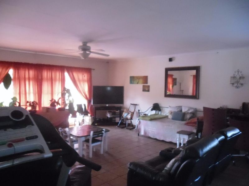 Spacious living area featuring tiled flooring and a ceiling fan, offering a versatile layout for comfortable family living.
