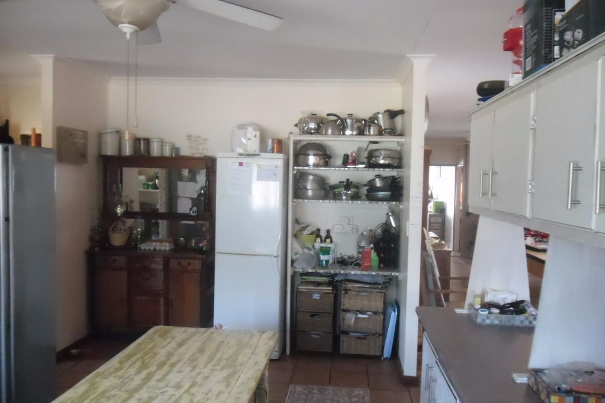 A functional kitchen area featuring built-in cabinetry, tiled flooring, and a ceiling fan, offering a practical layout for daily meal preparation.