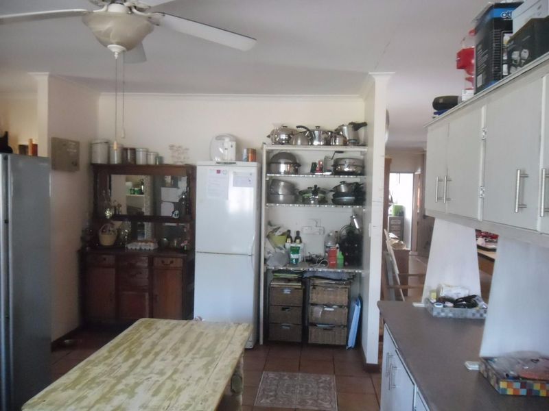 A functional kitchen area featuring built-in cabinetry, tiled flooring, and a ceiling fan, offering a practical layout for daily meal preparation.