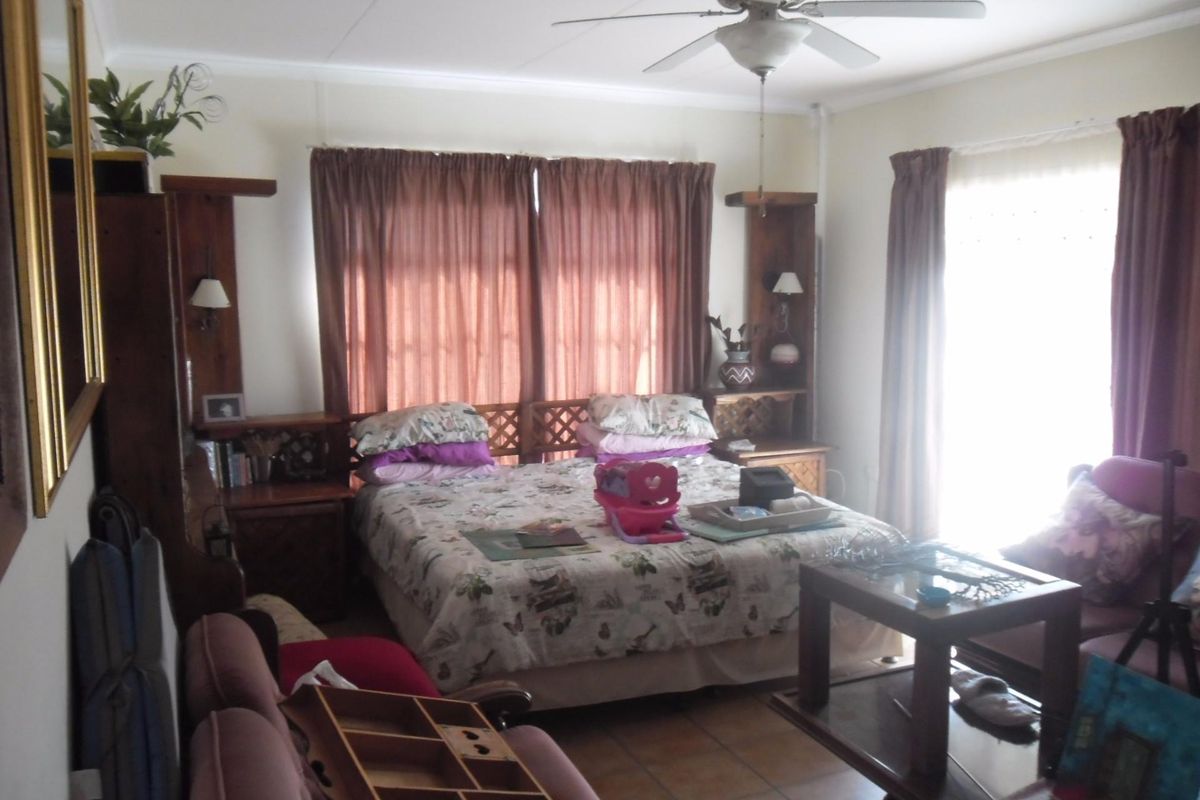A bedroom featuring tiled flooring, a ceiling fan, and built-in wooden headboard and bedside cabinetry.