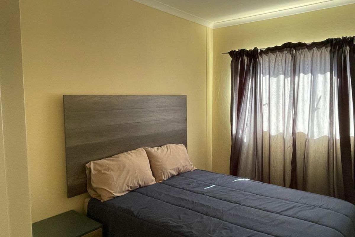 A standard bedroom featuring neutral wall finishes, a window with curtain tracks, and coved ceiling detailing.