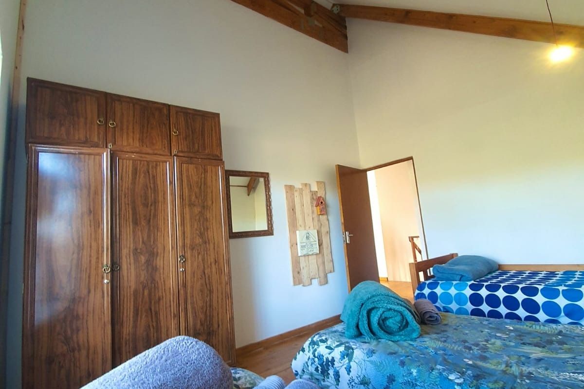 Spacious bedroom featuring high vaulted ceilings with exposed timber beams and built-in wooden cabinetry.