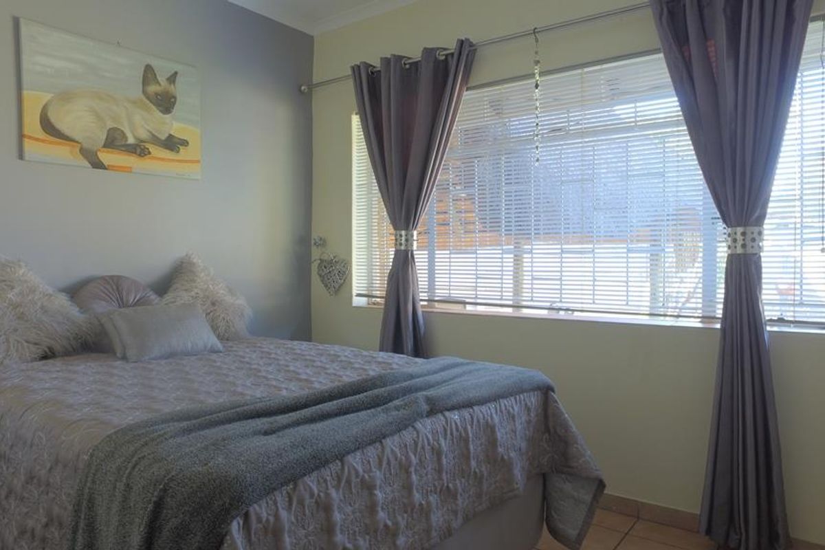 A bedroom featuring tiled flooring, built-in cupboard space, and a window with fitted blinds.