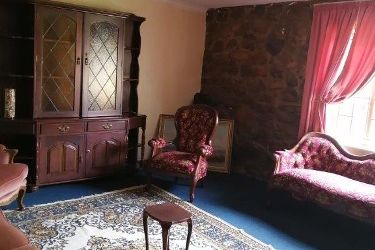 A living room featuring an exposed stone wall and carpeted flooring, requiring cosmetic updates to modernize the space.