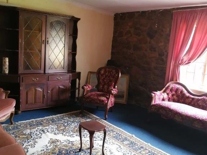 A living room featuring an exposed stone wall and carpeted flooring, requiring cosmetic updates to modernize the space.