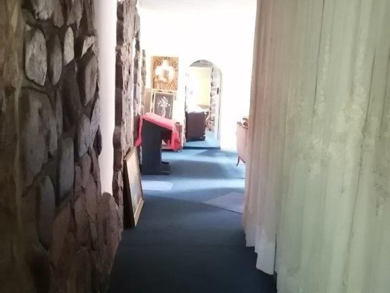 A long hallway featuring a prominent stone feature wall and an arched transition to the adjoining living space.