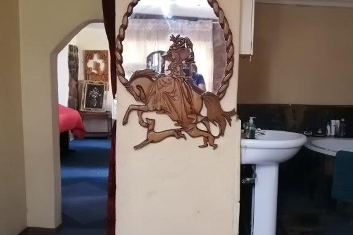 A bathroom area featuring a pedestal basin and an archway leading to an adjacent room, showcasing dated finishes and flooring.