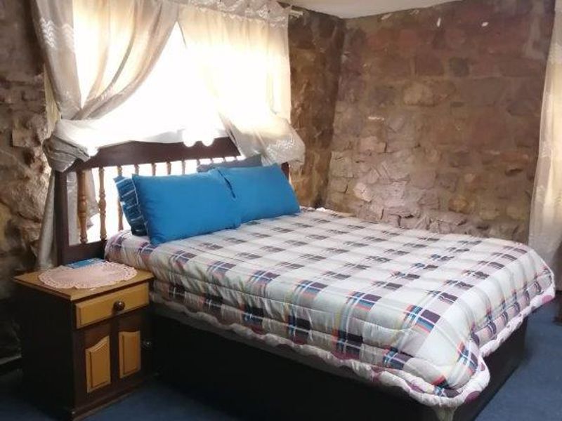 A bedroom featuring rustic exposed stone walls, providing a unique textured aesthetic to the living space.