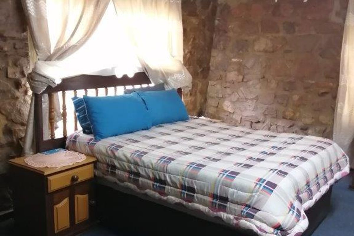 A bedroom featuring rustic exposed stone walls, providing a unique textured aesthetic to the living space.