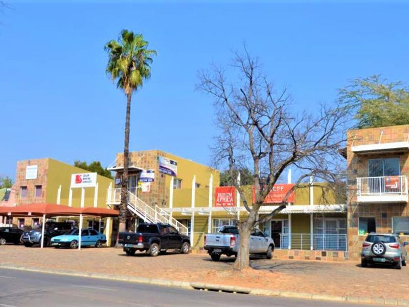 Front elevation of a commercial office complex featuring tiled facades, covered parking bays, and an external staircase leading to upper-level office units.