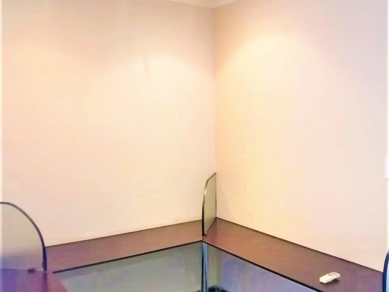 A functional office space featuring a built-in corner desk, tiled flooring, and recessed downlighting, providing a clean and professional work environment.