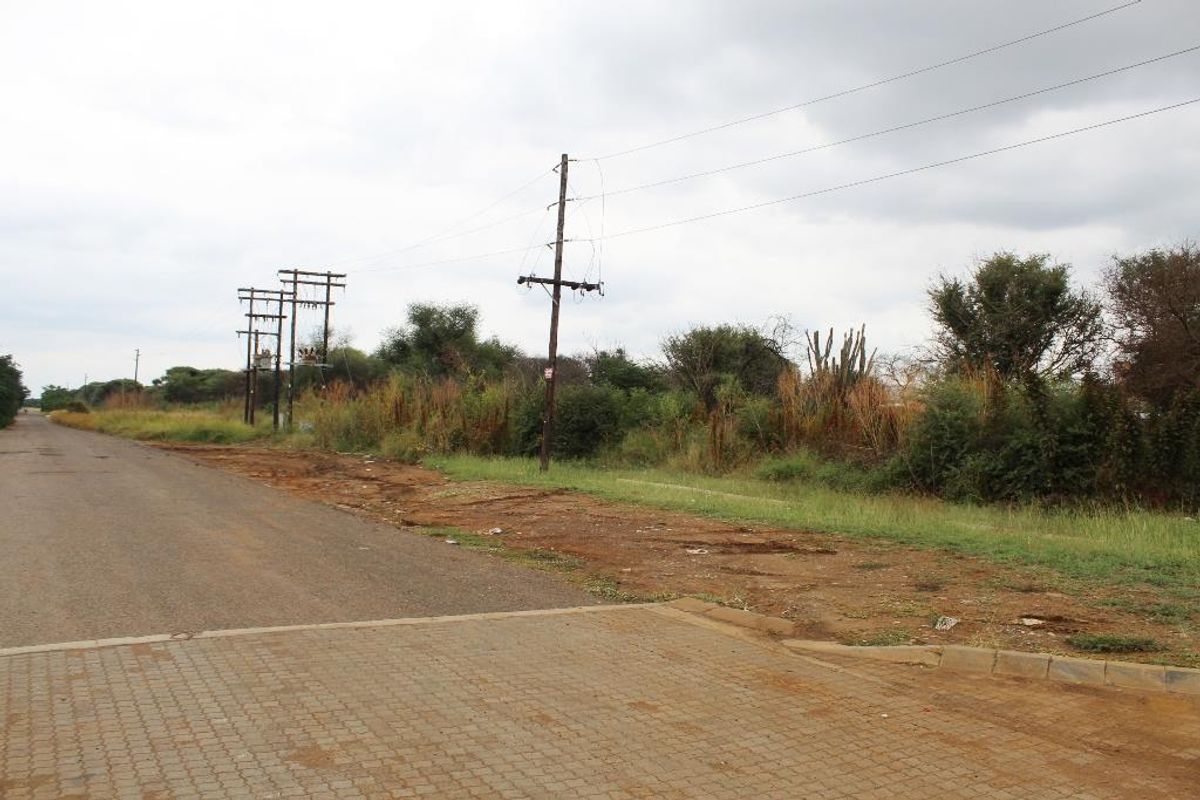 A street-level view of the vacant residential land, showing the adjacent paved road, verge, and existing utility infrastructure.