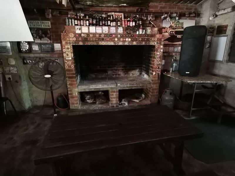 Rustic outdoor entertainment area featuring a large built-in brick fireplace and exposed brick walls, suitable for renovation to enhance the space.