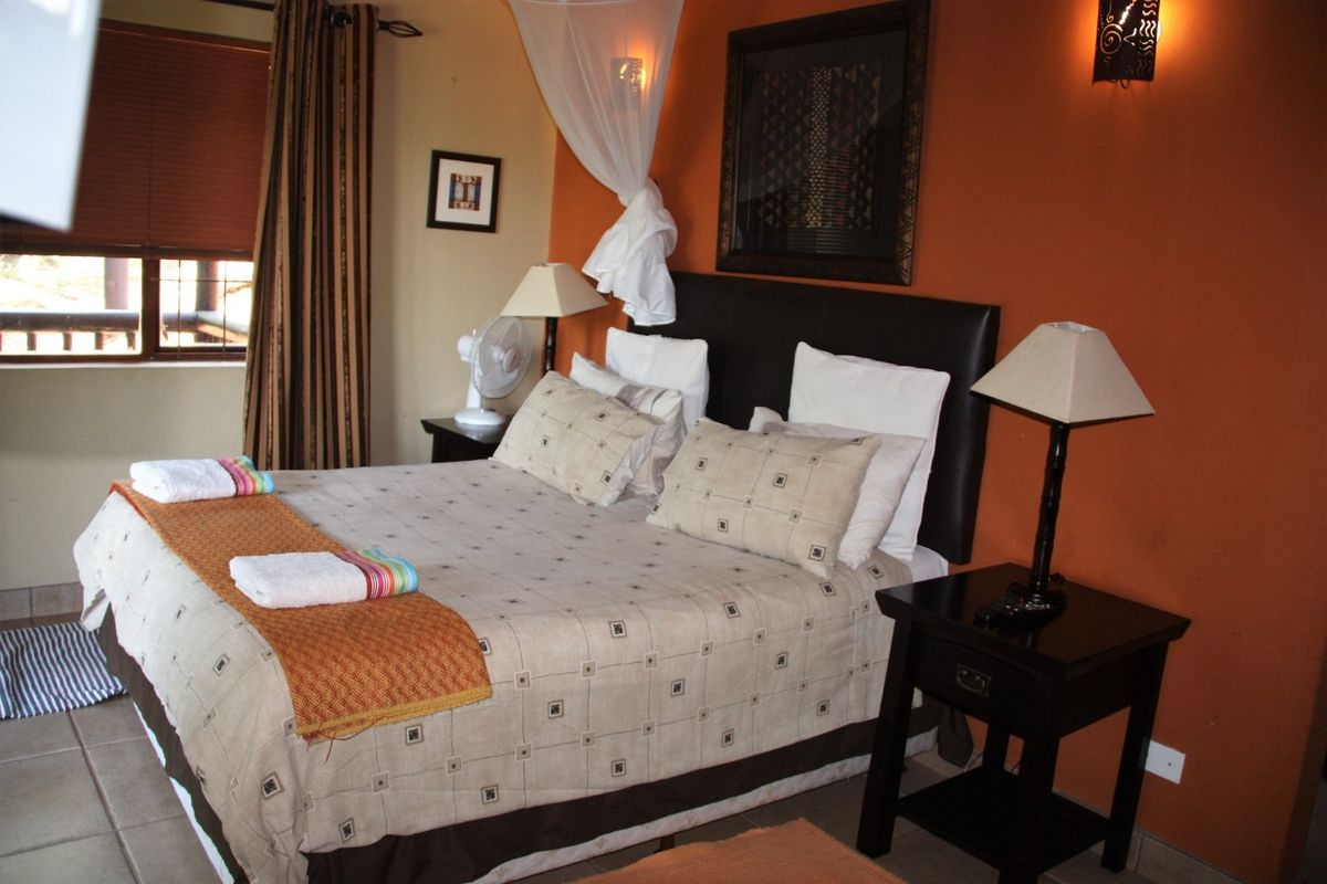 A bedroom featuring tiled flooring, warm-toned accent walls, and integrated wall lighting, providing a comfortable and functional sleeping space.