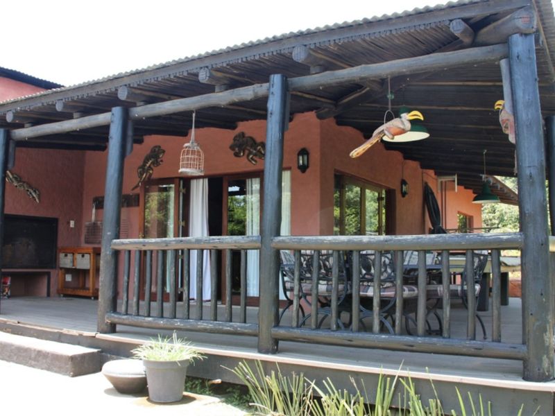 Spacious covered timber deck featuring a built-in braai, rustic timber support posts, and a corrugated roof, ideal for outdoor entertaining.