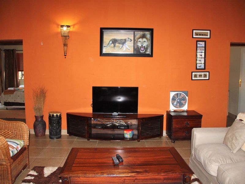 A living room featuring tiled flooring and a wall-mounted light fixture, with access to adjacent rooms.