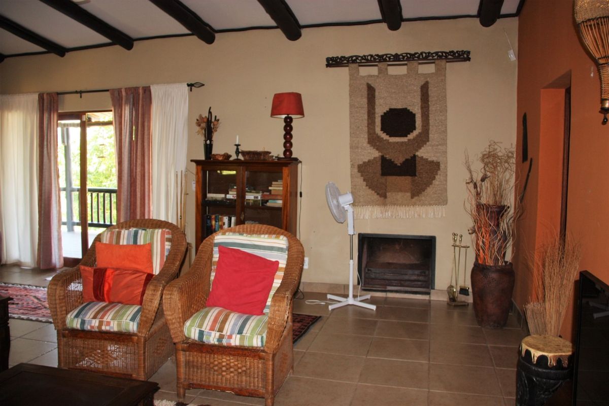Living room featuring exposed timber ceiling beams, tiled flooring, and a built-in fireplace with access to an outdoor area via sliding glass doors.