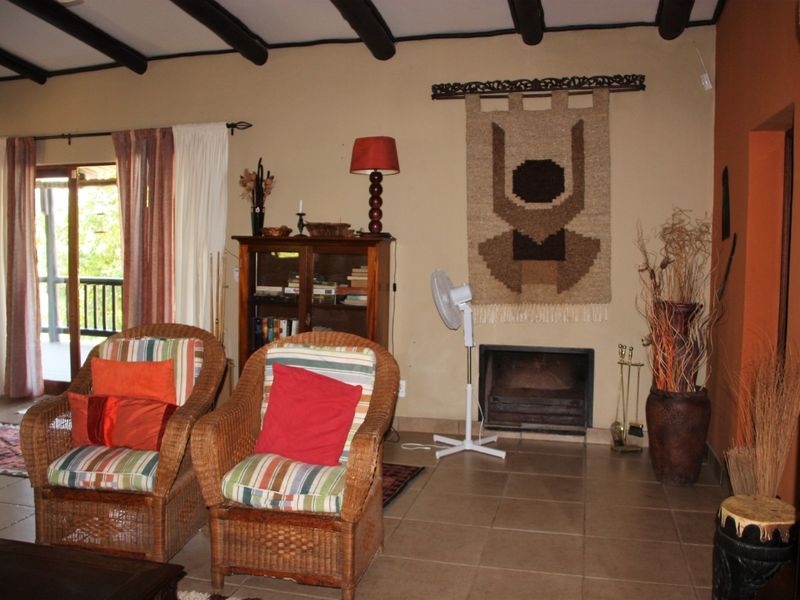 Living room featuring exposed timber ceiling beams, tiled flooring, and a built-in fireplace with access to an outdoor area via sliding glass doors.