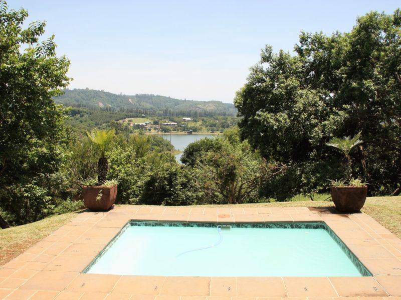 A well-maintained swimming pool with a tiled surround, offering scenic views of the surrounding landscape and lake.