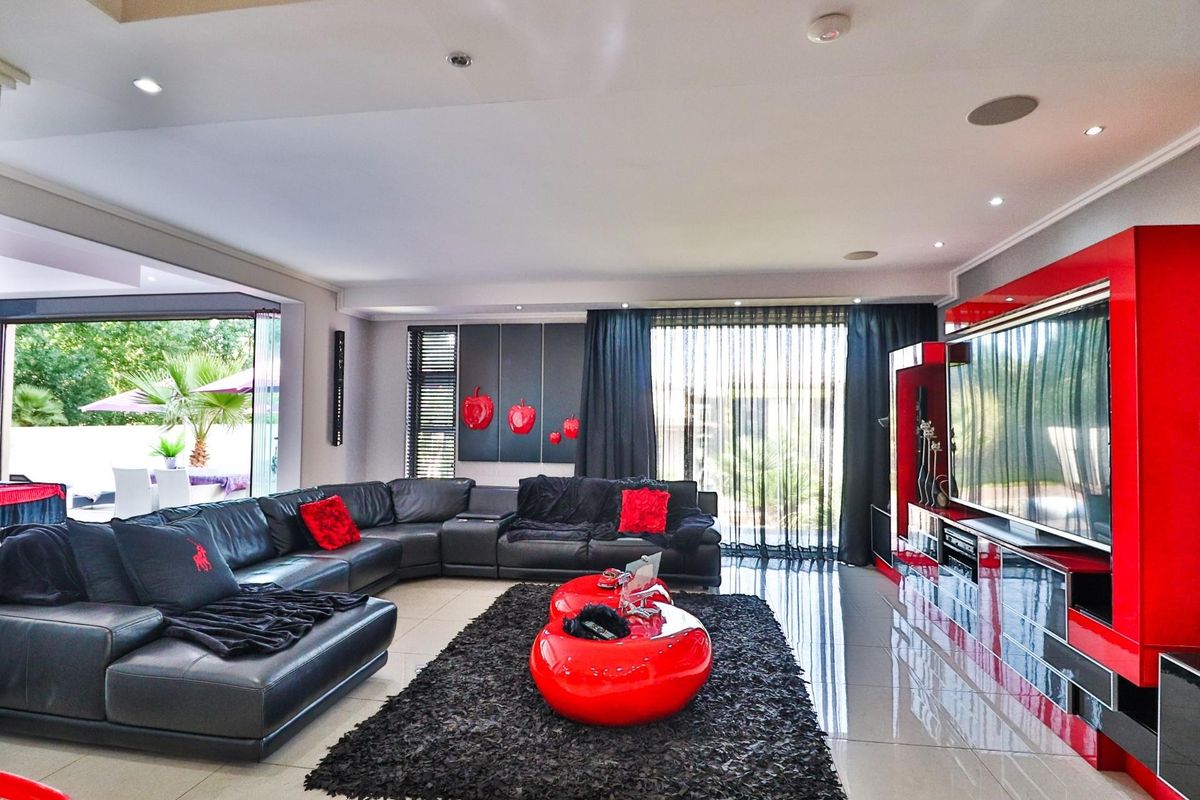 Spacious modern living room featuring large format floor tiles, recessed ceiling lighting, integrated sound system, and seamless access to an outdoor patio area.