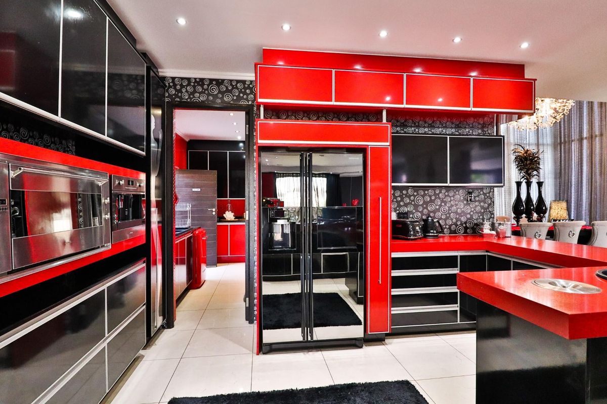 Modern kitchen featuring high-gloss red and black cabinetry, integrated appliances, and a breakfast bar with a sleek countertop.