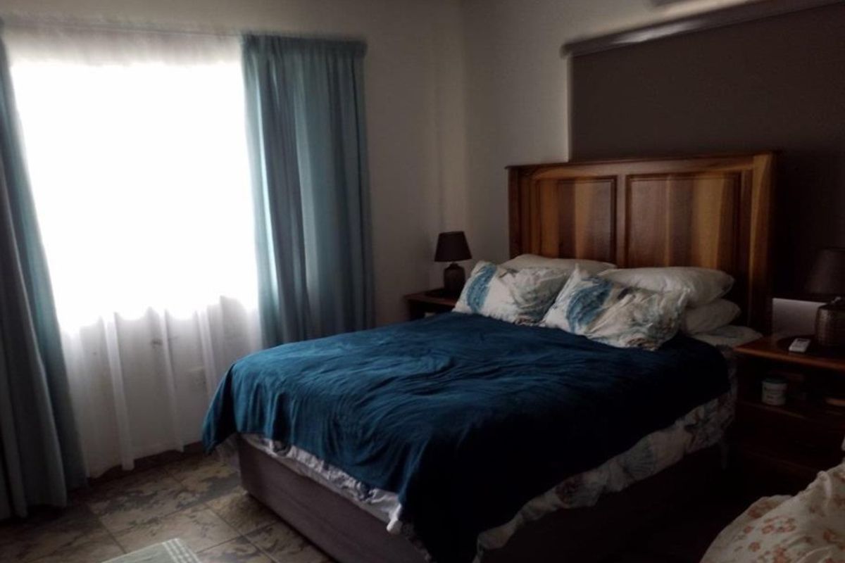 A bedroom featuring tiled flooring and a window with curtains, providing a functional and comfortable sleeping space.