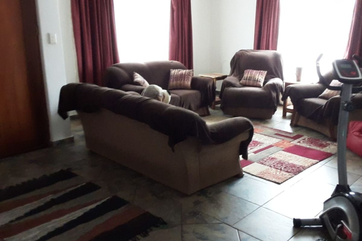 A spacious living room featuring tiled flooring and large windows that provide ample natural light, creating a comfortable and functional living space.