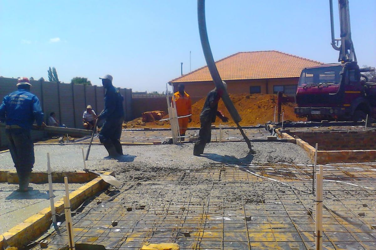 Construction site showing the pouring of a concrete foundation slab for a new residential building.