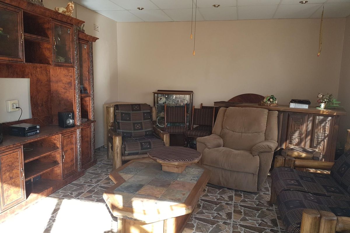 A living room featuring tiled flooring, recessed lighting, and a ceiling fan, currently showing signs of wear and dated finishes.