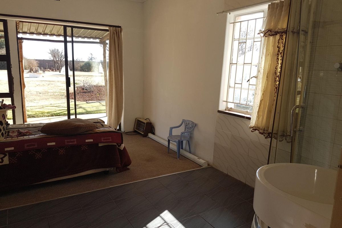 A bedroom featuring an en-suite shower, sliding door access to the garden, and a combination of tiled and carpeted flooring.