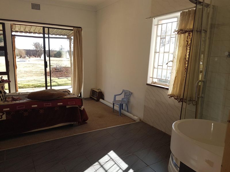 A bedroom featuring an en-suite shower, sliding door access to the garden, and a combination of tiled and carpeted flooring.