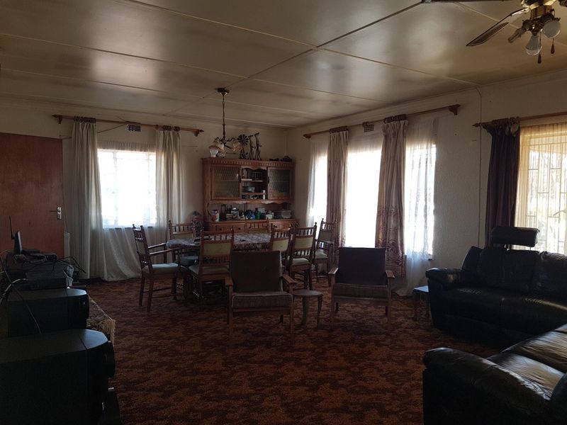Spacious open-plan living and dining area featuring a ceiling fan and built-in cabinetry, offering significant potential for modernization and renovation.