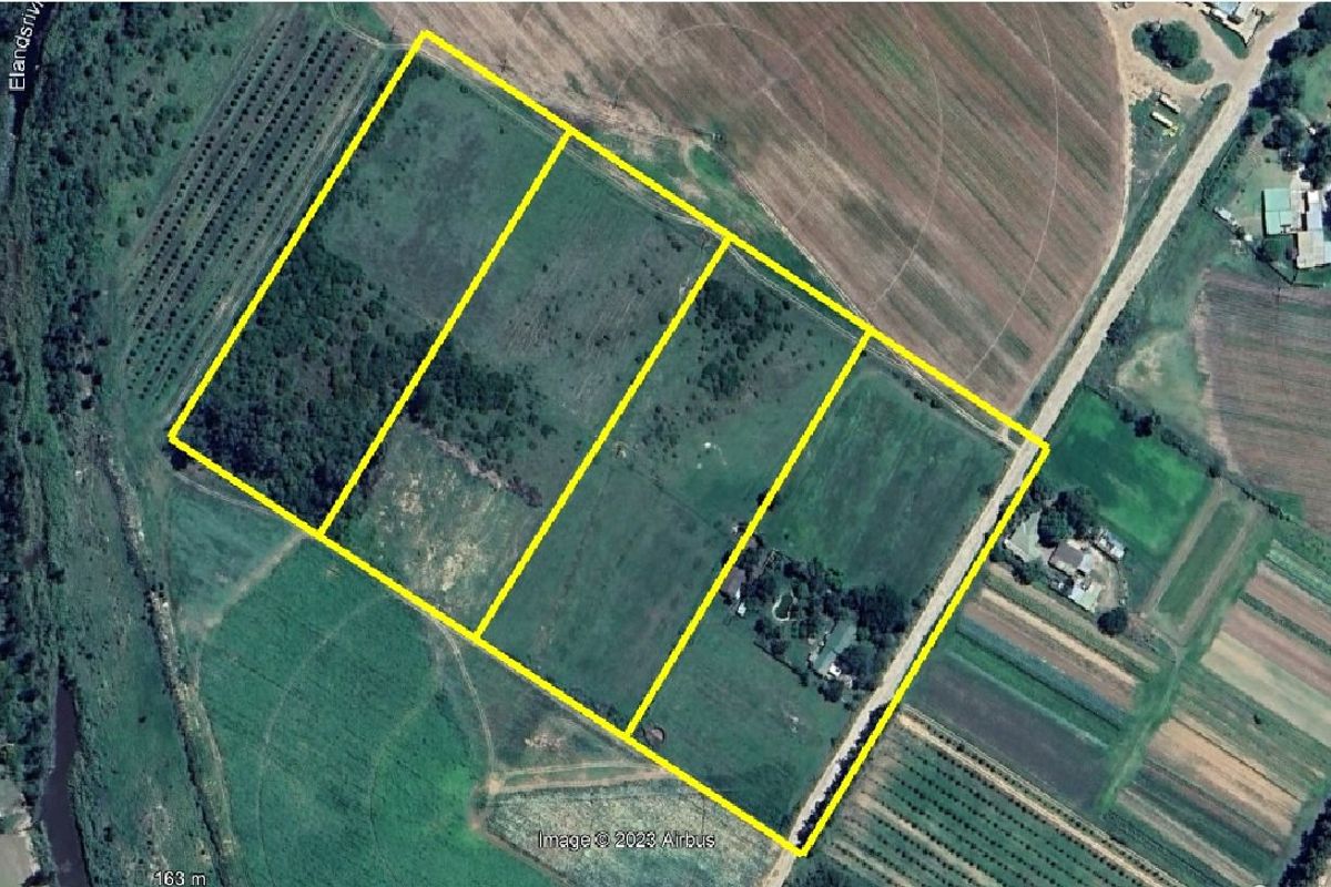 Aerial view of a large farm property featuring multiple fenced land parcels, agricultural fields, and existing farmstead infrastructure.