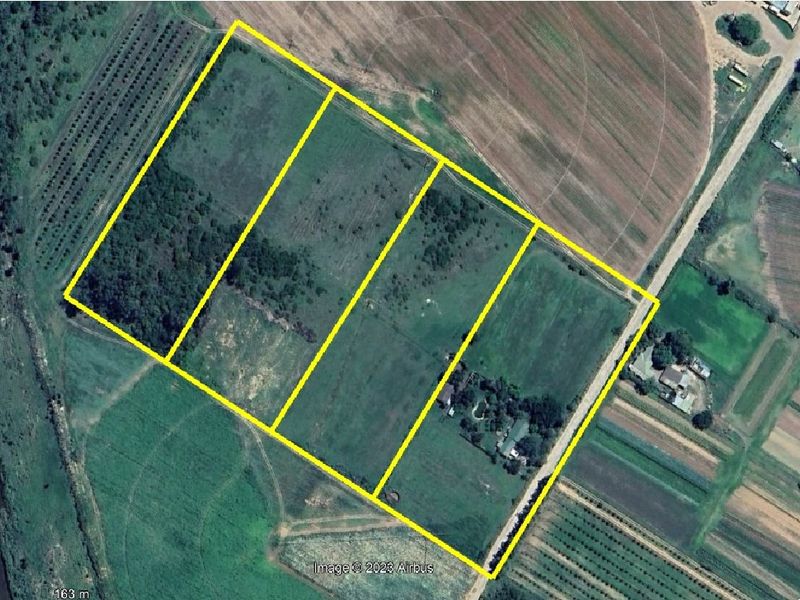 Aerial view of a large farm property featuring multiple fenced land parcels, agricultural fields, and existing farmstead infrastructure.