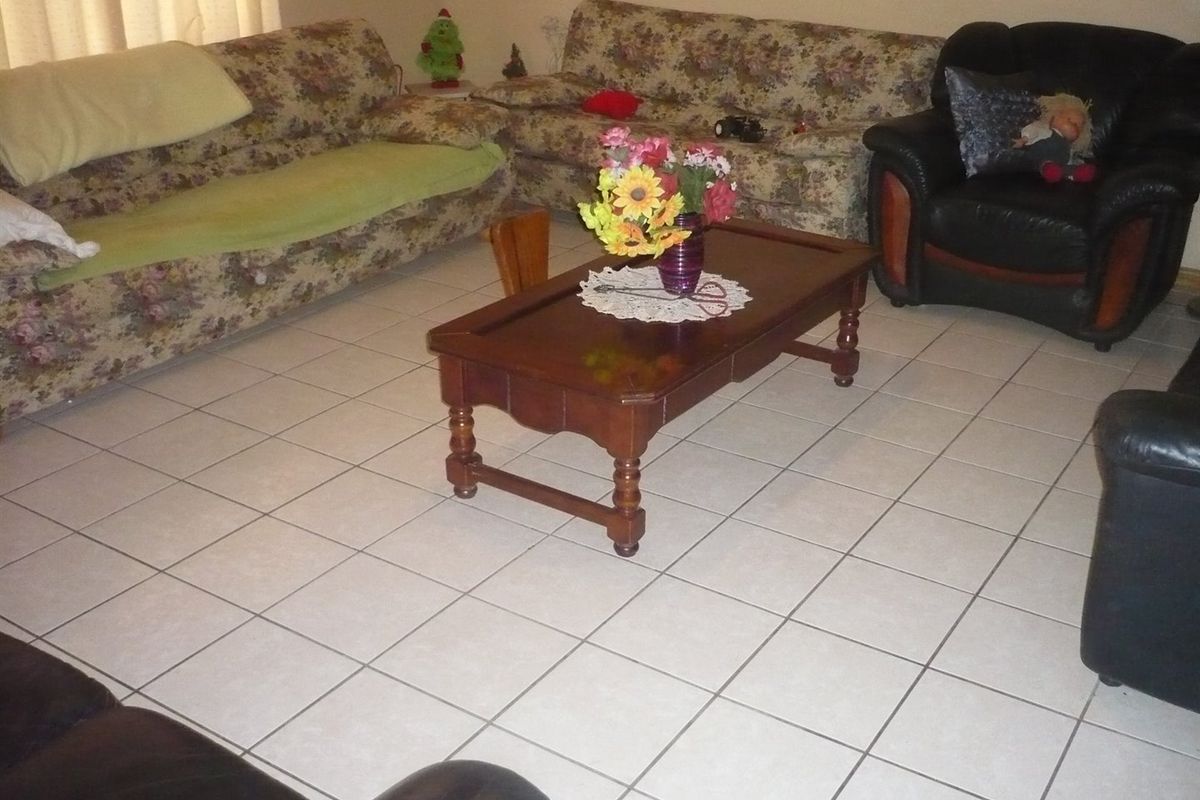 A living room area featuring neutral ceramic floor tiles, providing a functional and easily maintainable base for the space.