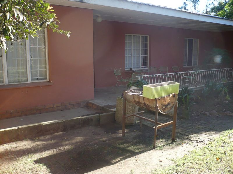 A covered outdoor patio area featuring brick paving and metal security railings, showing signs of exterior wear and requiring maintenance.