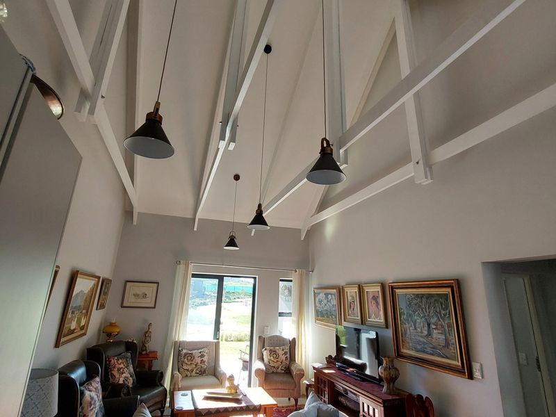 Open-plan living area featuring a high vaulted ceiling with exposed trusses, pendant lighting, and a modern kitchen island with a built-in gas hob.