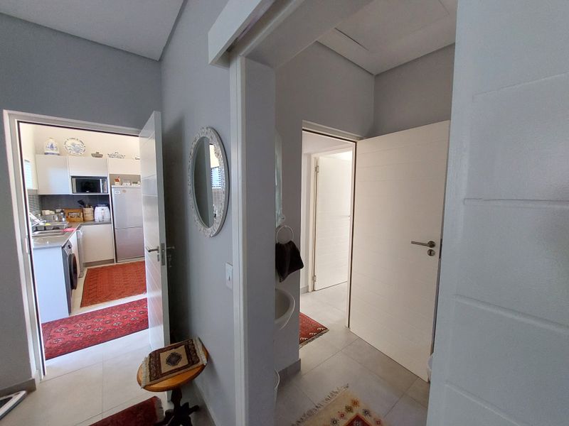 A bright, neutral hallway providing access to the kitchen and adjacent rooms, featuring clean tiled flooring and modern internal doors.