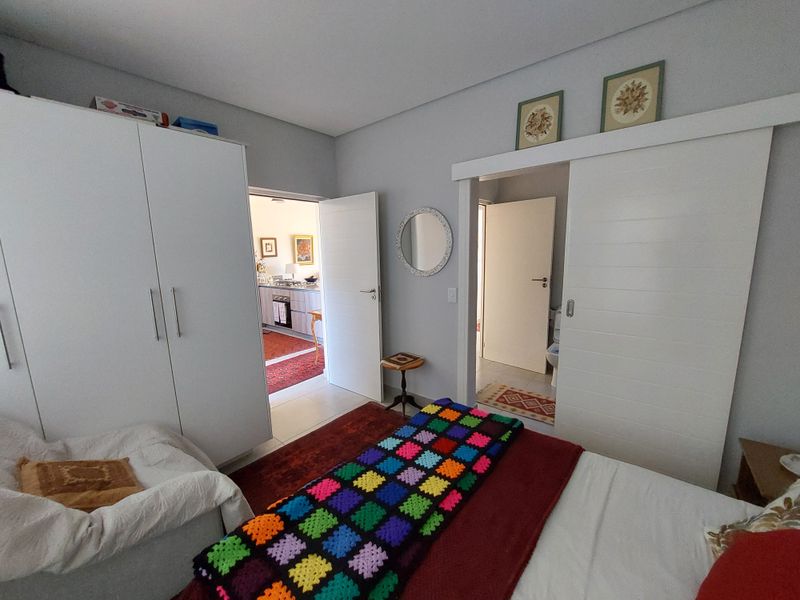 A well-maintained bedroom featuring built-in wardrobes and a sliding door providing access to an en-suite bathroom.