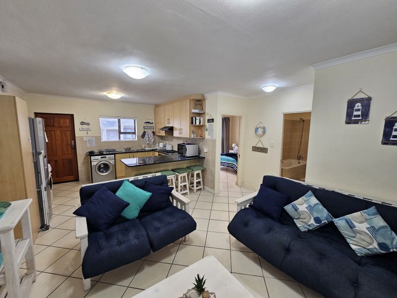 Open plan living area featuring a functional kitchen with granite countertops, tiled flooring, and direct access to adjacent bedroom and bathroom spaces.