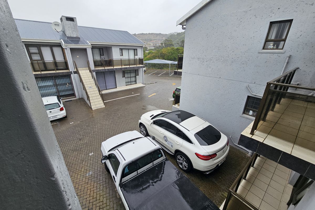 An elevated view of the apartment complex courtyard featuring paved parking areas, external staircases, and balcony access.
