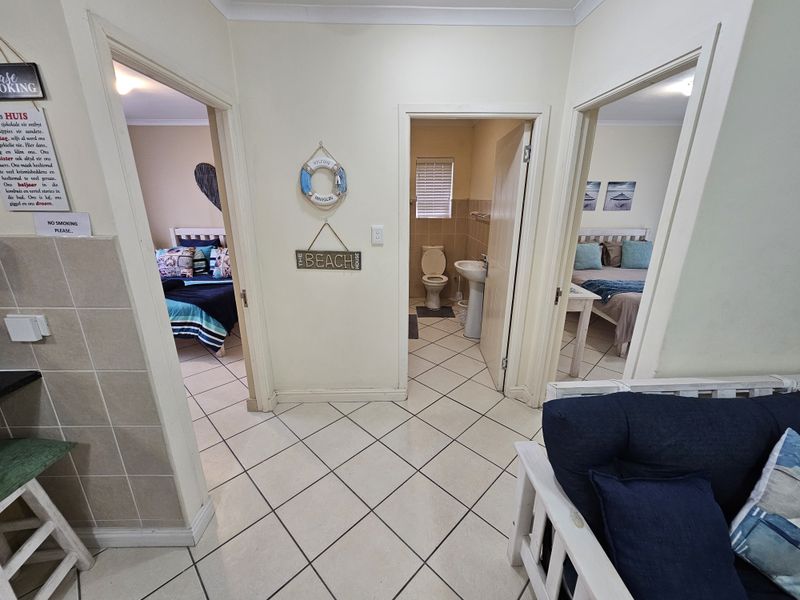 A central hallway providing access to two bedrooms and a bathroom, featuring neutral tiled flooring and standard interior door frames.