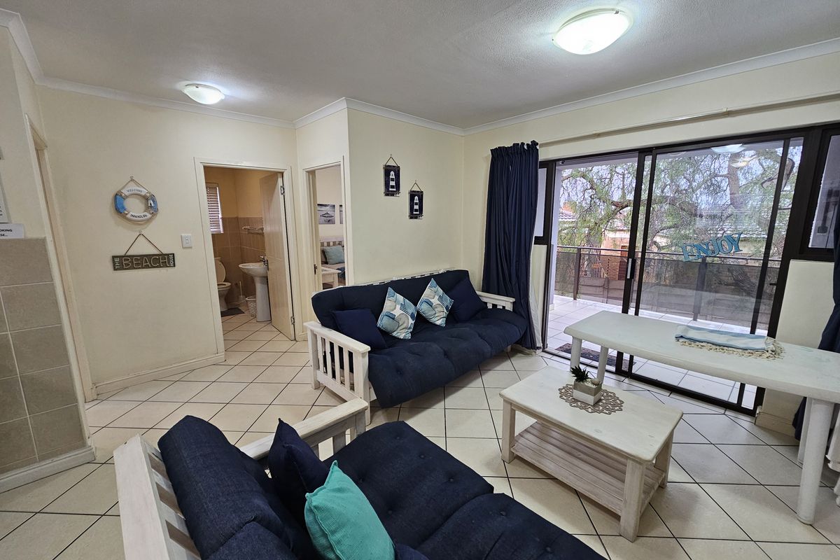 Open-plan living area featuring tiled flooring, coved cornices, and large sliding glass doors providing access to an outdoor balcony.
