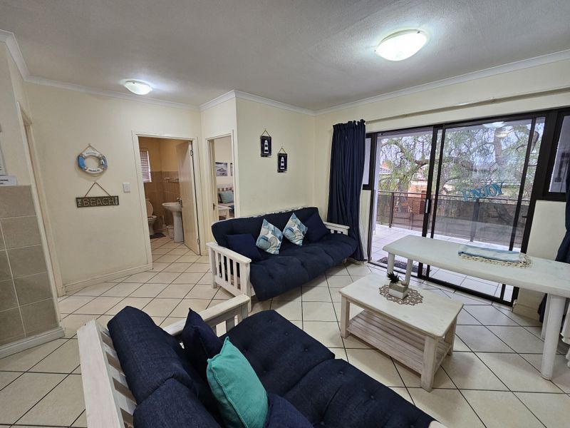 Open-plan living area featuring tiled flooring, coved cornices, and large sliding glass doors providing access to an outdoor balcony.