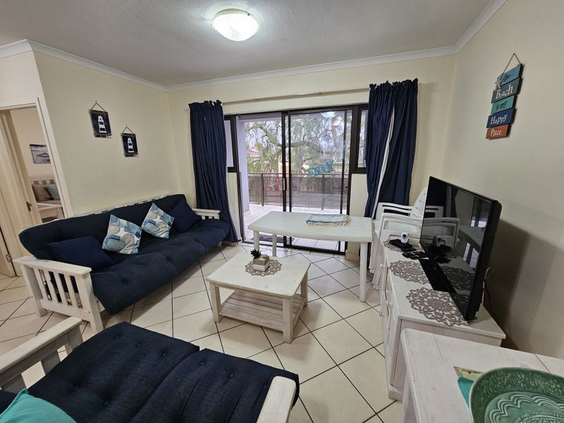 A living room featuring ceramic floor tiles, coved cornices, and a sliding glass door providing access to an outdoor balcony area.